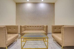 Una habitación con sofá beige, una mesa de centro de vidrio y piso de mármol.