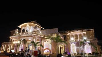 A grand building with multiple balconies, ornate arches, and a well-lit entrance.