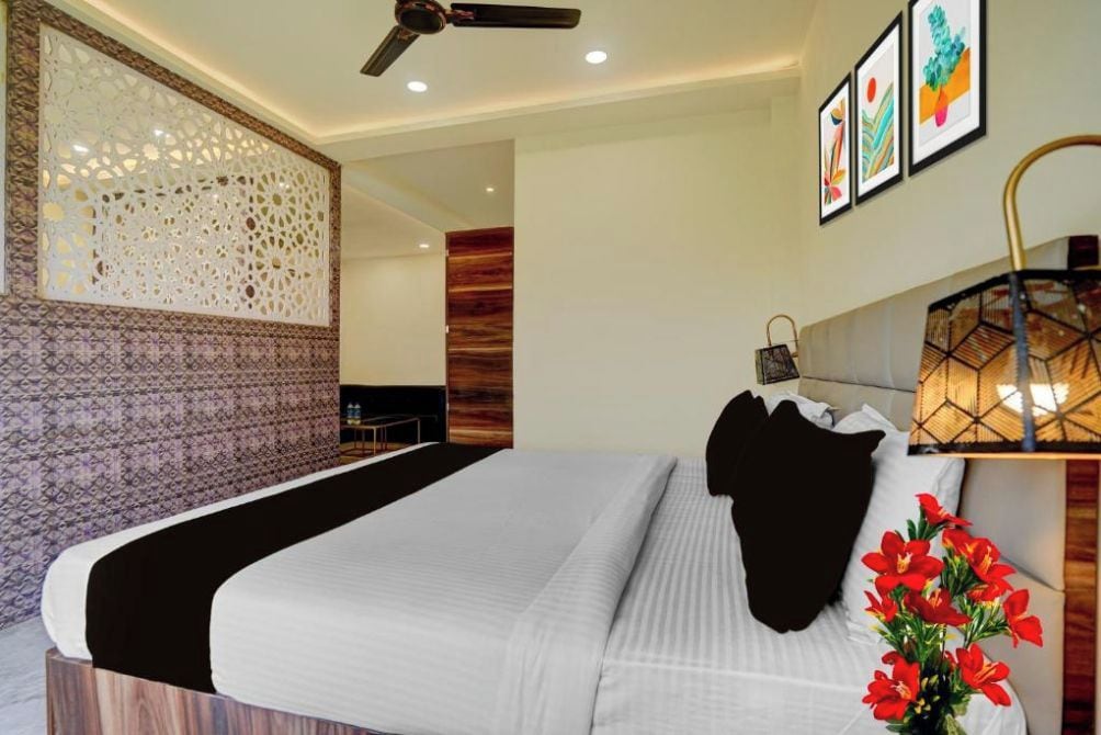 Une chambre d’hôtel moderne avec un grand lit, un ventilateur de plafond, un panneau décoratif au mur et des œuvres d’art encadrées accrochées au mur.