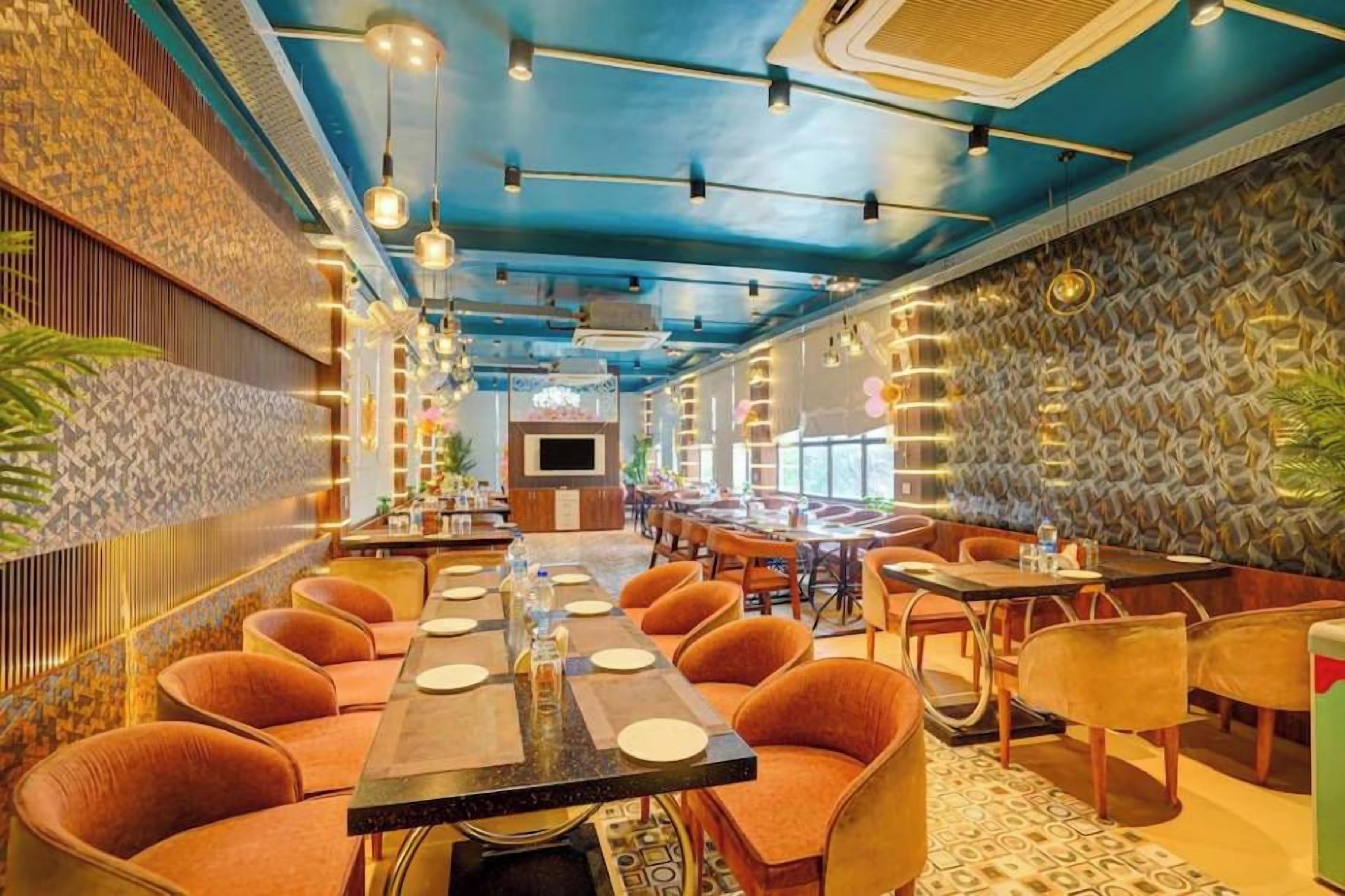 A restaurant with a long communal table, individual tables, and orange chairs.