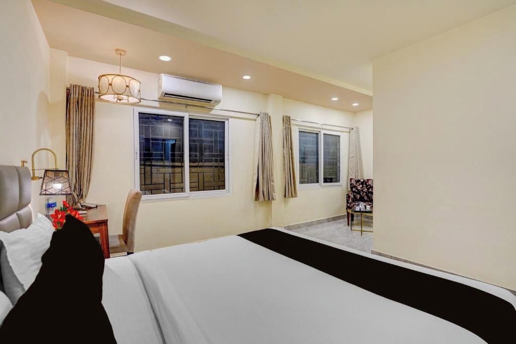 Habitación de hotel con cama, escritorio, silla y ventana con cortinas.