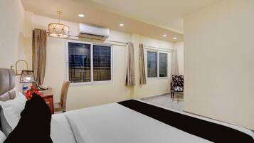 Habitación de hotel con cama, escritorio, silla y ventana con cortinas.