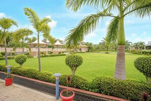 A well-maintained garden with palm trees, neatly trimmed hedges, and a clear sky. - Amar Resorrt Motihari Bihar (Motihari)