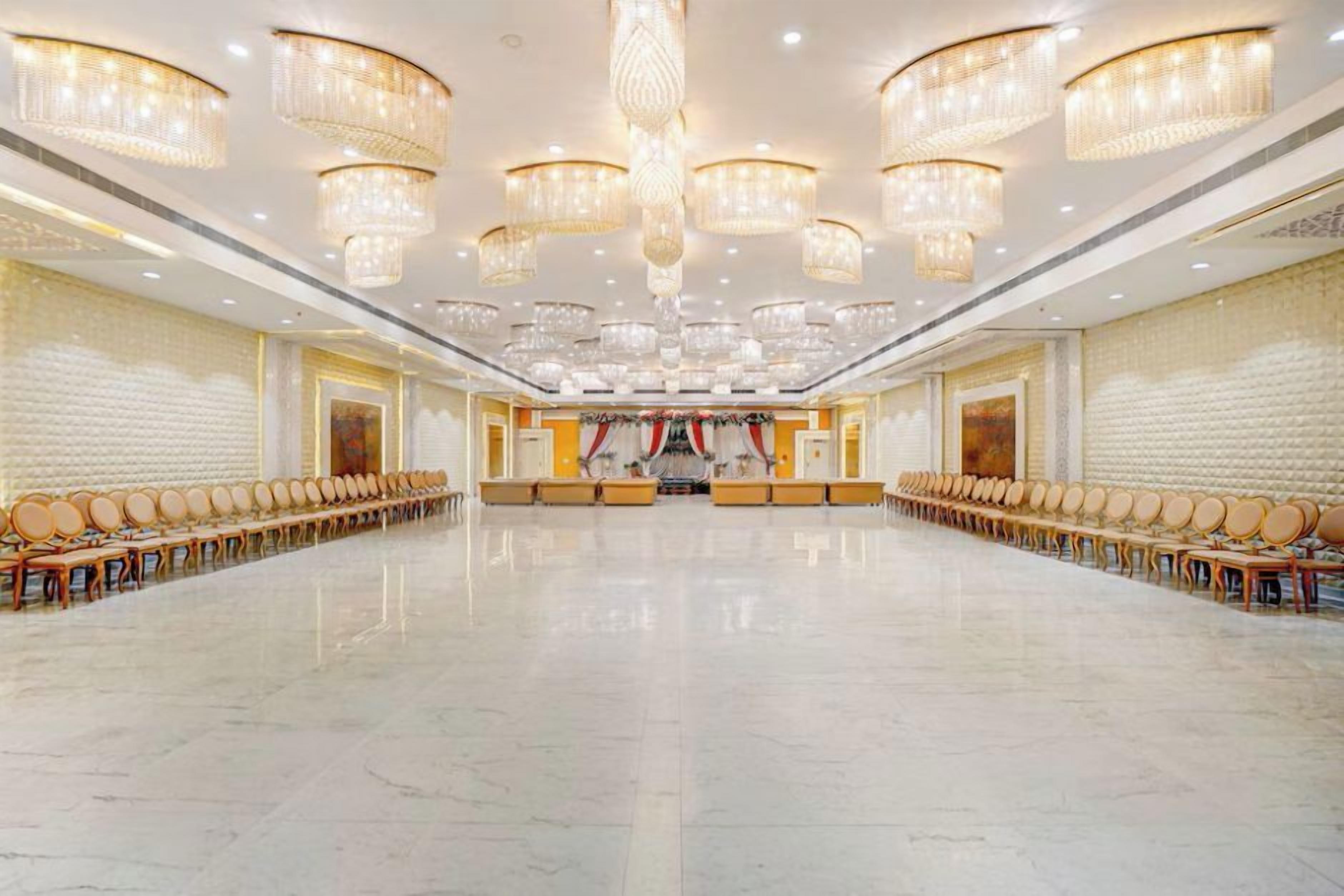 A spacious conference room with a long table and rows of chairs, large chandeliers, and a polished floor.