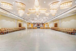 A spacious conference room with a long table and rows of chairs, large chandeliers, and a polished floor. - Amar Resorrt Motihari Bihar (Motihari)