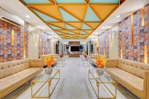 Een hotellobby met een modern design, met een centraal zithoek met banken en een ronde tafel, en behang met een patroon.