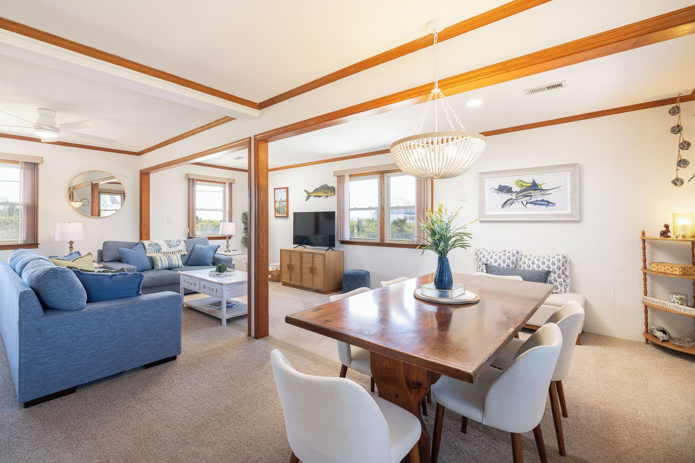 A spacious living area with a wooden dining table, a blue sofa, and a television in the background.