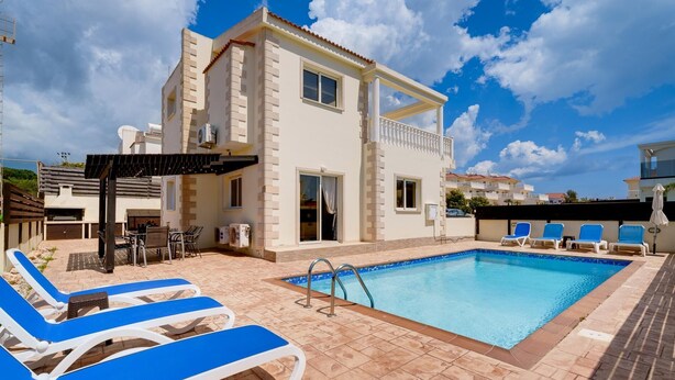 Un edificio moderno de dos pisos con piscina, mobiliario exterior y una pérgola.