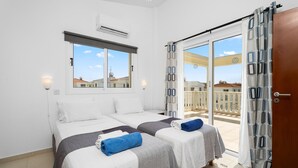 Habitación de hotel con dos camas, un balcón y vistas a edificios.