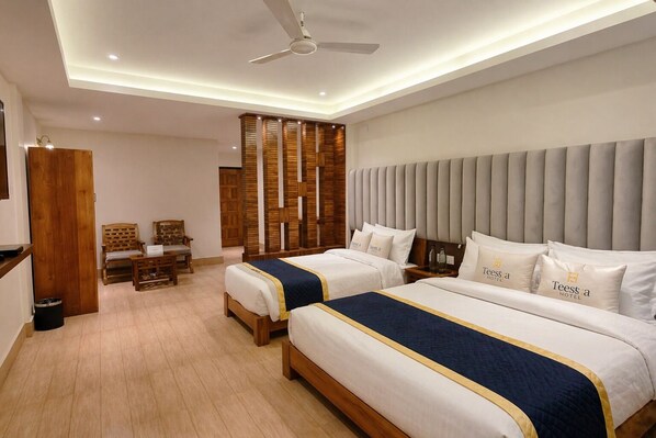 A hotel room with two beds, a desk, chairs, a wooden partition, and a ceiling fan. - Teesta Hotels Kalimpong (Kalimpong)