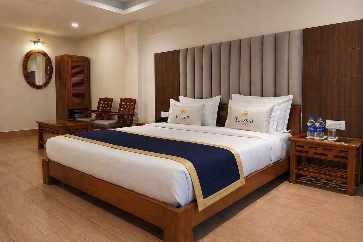 A hotel room with a large bed, wooden headboard, two bedside tables, a mirror, and a wooden wardrobe.
