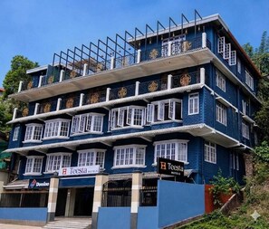 Un hôtel à plusieurs étages, doté d’une façade bleue, de nombreux balcons et d’enseignes indiquant « Teesta Hotels » et « Domino ».