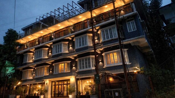 A multi-story hotel with balconies, a well-lit entrance, and a gated driveway.
