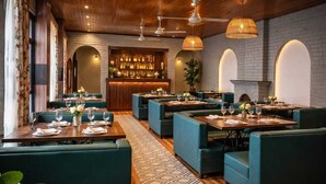 A restaurant with multiple tables and booths, a bar area, and a patterned floor.