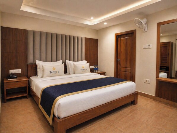 Una habitación de hotel con cama, mesitas de noche, un espejo y un ventilador de pared.