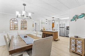 A modern kitchen with a central island, stainless steel appliances, and a dining area with a wooden table and chairs. - The Reel Escape! St. James City 2/2 with Boat Lift! (Saint James City)