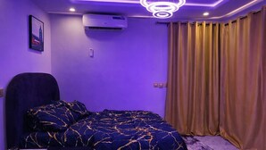 Ein Schlafzimmer mit einem Bett, einem Schreibtisch, einer Klimaanlage und einem Vorhang.