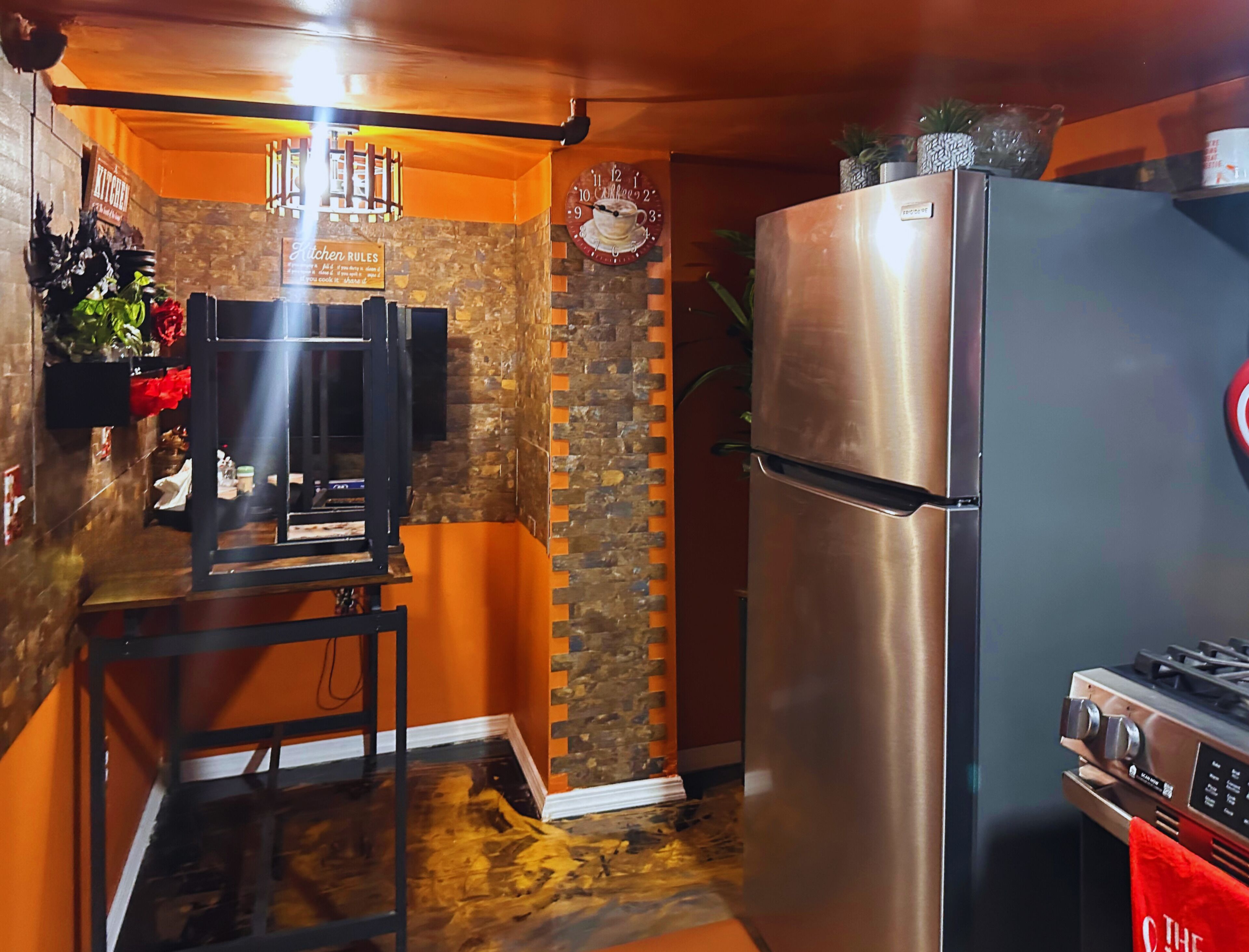 Een keuken met een roestvrijstalen koelkast, een fornuis en een bakstenen muur.