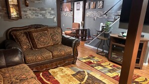 Ein Wohnzimmer mit einer Couch, einem Couchtisch, einem Kamin und einer Treppe.