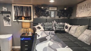 Ein Schlafzimmer mit einem Bett, Nachttischen, einer Lampe, einer Uhr und dekorativen Kissen.