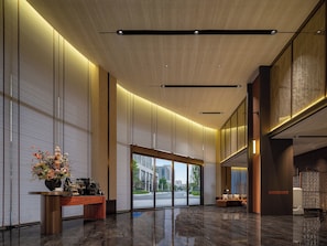 Um hall moderno com balcão de recepção, uma janela grande e área de estar.