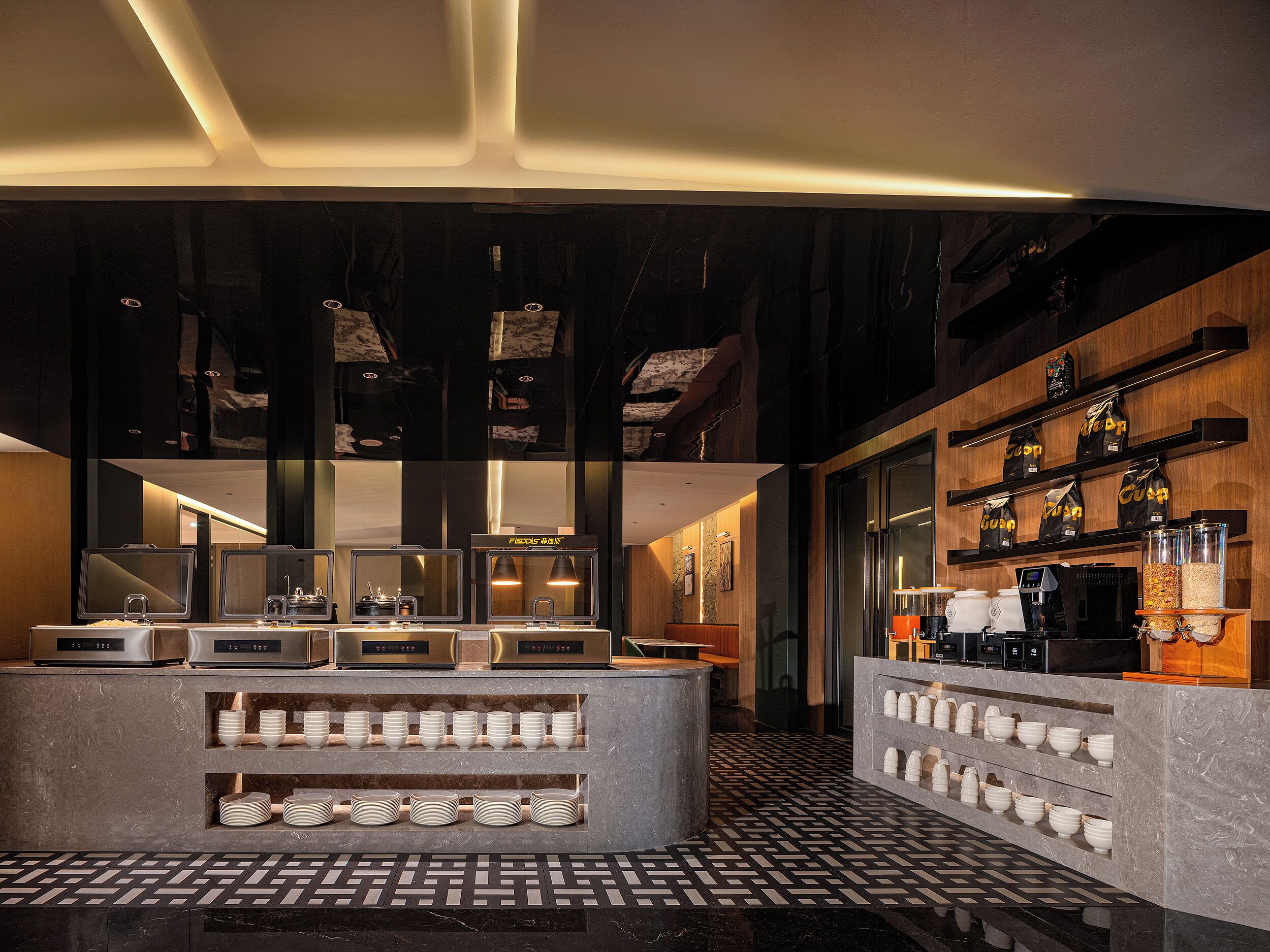 Un espace bar moderne doté d’un comptoir en marbre, de machines à café et d’étagères remplies de paquets de café.