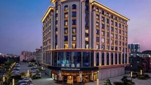 Un hotel de varios pisos con fachada curva, ventanas amplias y una entrada bien iluminada.