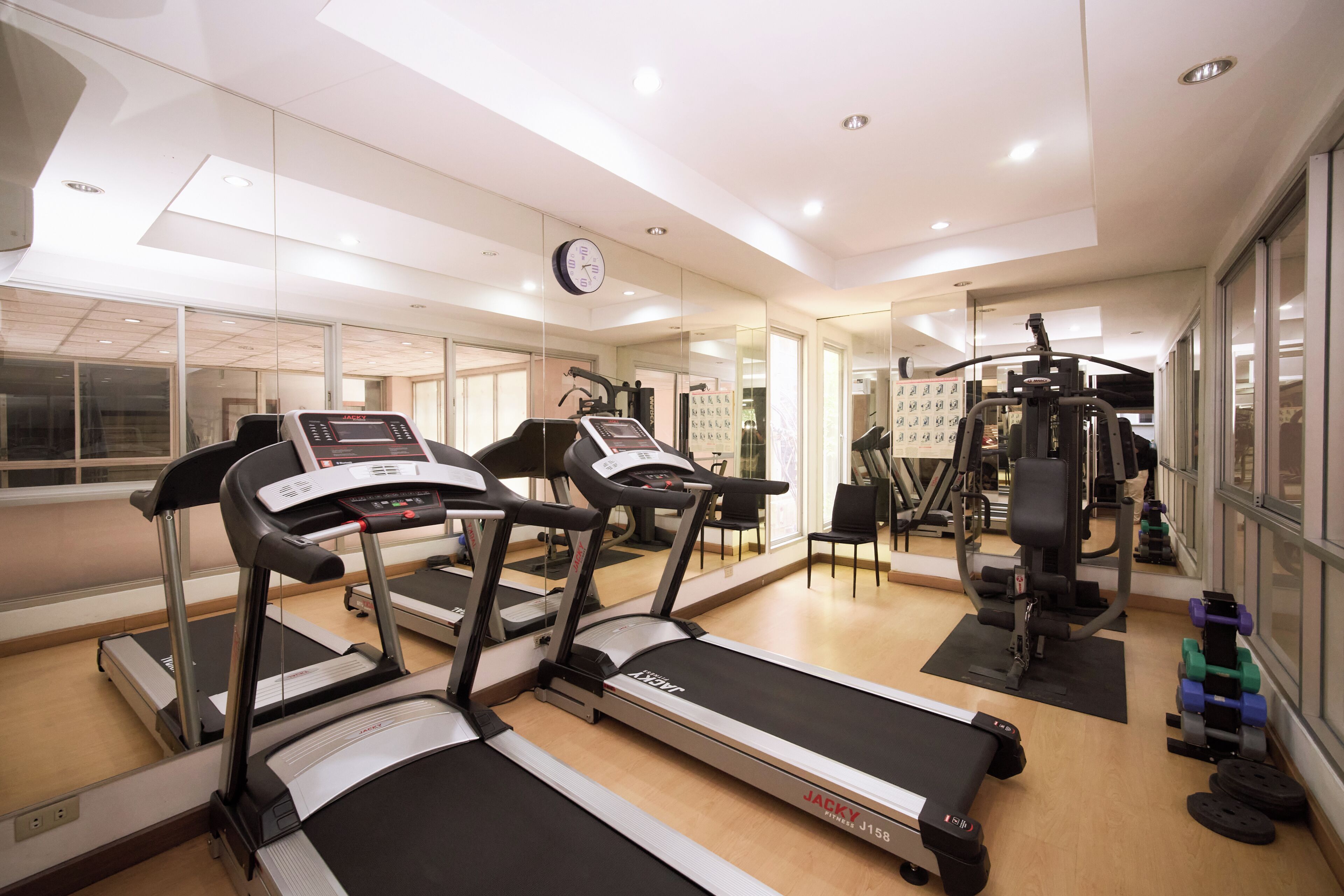 Une salle de sport équipée de tapis de course, d’appareils de musculation et d’un mur recouvert de miroirs.