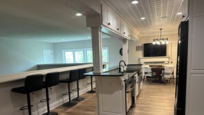 Une cuisine moderne avec un coin bar, un plancher en bois et une vue sur l’extérieur.