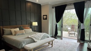 Une chambre à coucher comprenant un lit, un banc, une table de chevet, une lampe et une vue sur l’extérieur.