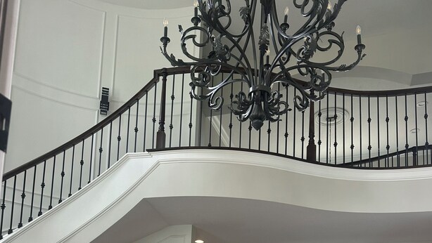 Un intérieur spacieux agrémenté d’un magnifique escalier, d’un lustre, d’un coin repas et offrant une vue imprenable grâce à de grandes fenêtres.