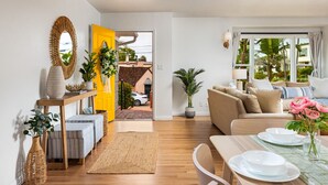 Ein modernes Wohnzimmer mit einer Couch, einem Esstisch und einer gelben Tür, die nach draußen führt.