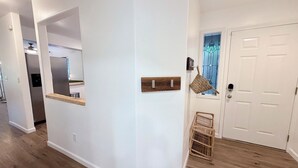 Um corredor com uma porta branca, piso de madeira e uma cesta fixada na parede.