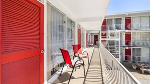 A balcony with red shutters, a white railing, and a table with chairs. - Oceanview Condo Steps from Beach & Boardwalk in North Wildwood (Wildwood)
