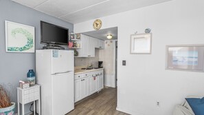 A compact kitchen with white cabinets, a refrigerator, a microwave, and a television. - Oceanview Condo Steps from Beach & Boardwalk in North Wildwood (Wildwood)