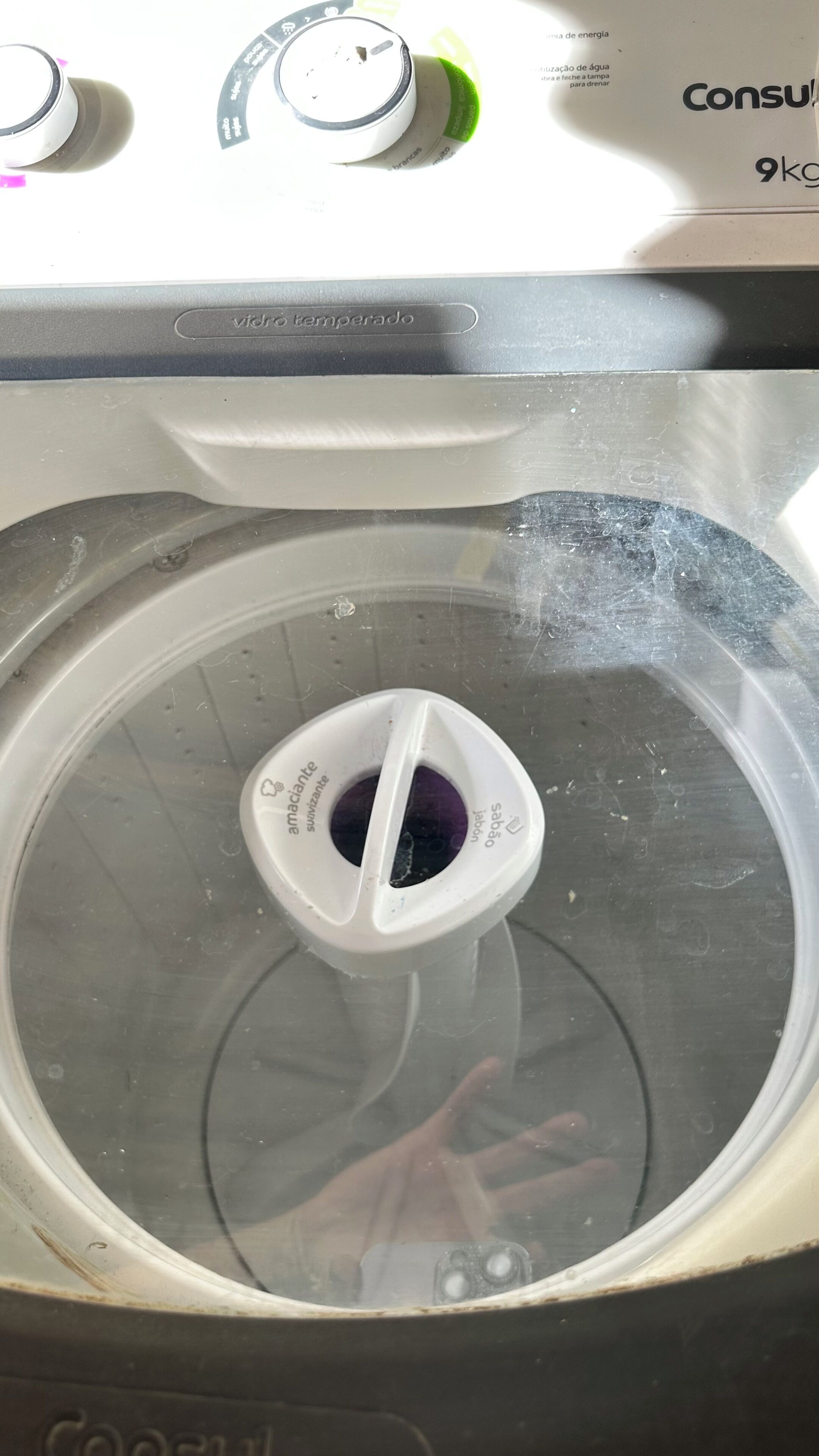 A washing machine with a transparent lid, a control panel with a digital display, and a brand name 'Consul' visible.