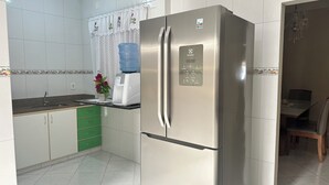 Una cocina con refrigerador de acero inoxidable, dispensador de agua, cafetera y pileta.