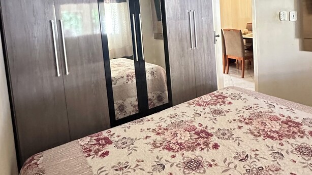 Un dormitorio con cama, armario, ventilador de techo y una zona de comedor al fondo.