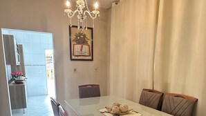 Un comedor con una mesa larga, sillas, una lámpara de araña y vistas a otra habitación.