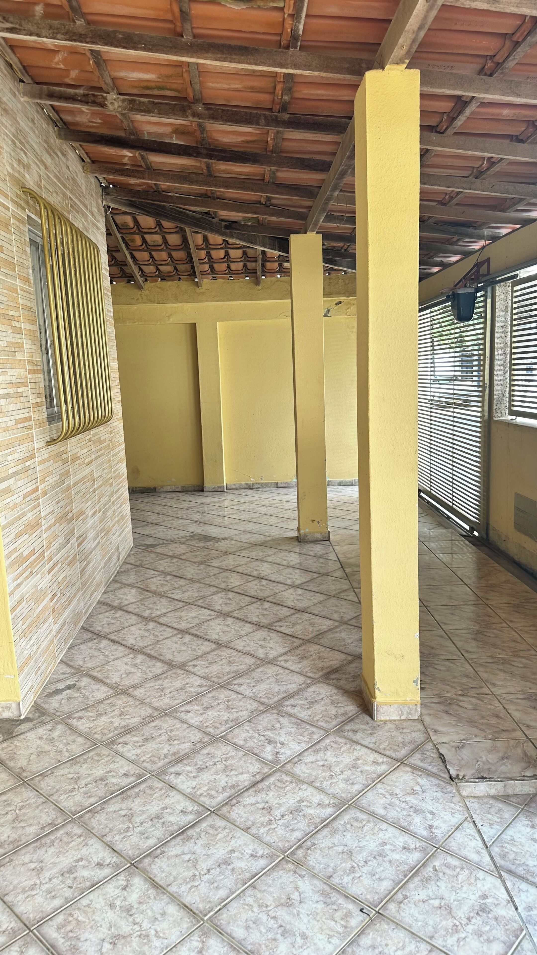 Um espaço interno amplo, com piso e teto azulejados, e paredes amarelas.