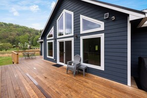 A house with a deck, large windows, and a chair.