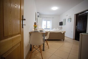 Ein Zimmer mit Bett, Schreibtisch mit Stuhl, Fernseher und Fenster.