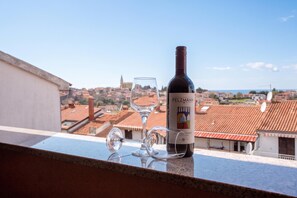 A bottle of wine and a glass on a balcony overlooking a cityscape with terracotta rooftops. - Lovely Studio Apartment 5 Vrsar, Vrsar, Croatia (Vrsar)