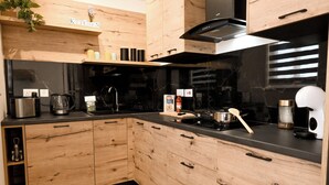 A modern kitchen with wooden cabinets, a black countertop, and various appliances. - Viviani Court 2bd Modern Apt Xewkija Gozo, XEWKIJA Gozo, Malta (XEWKIJA Gozo)