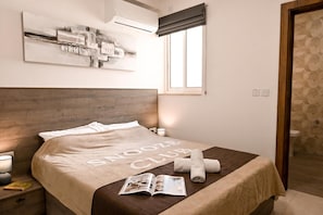 Una camera d'albergo con un letto, una finestra, una porta e un condizionatore d'aria a parete.