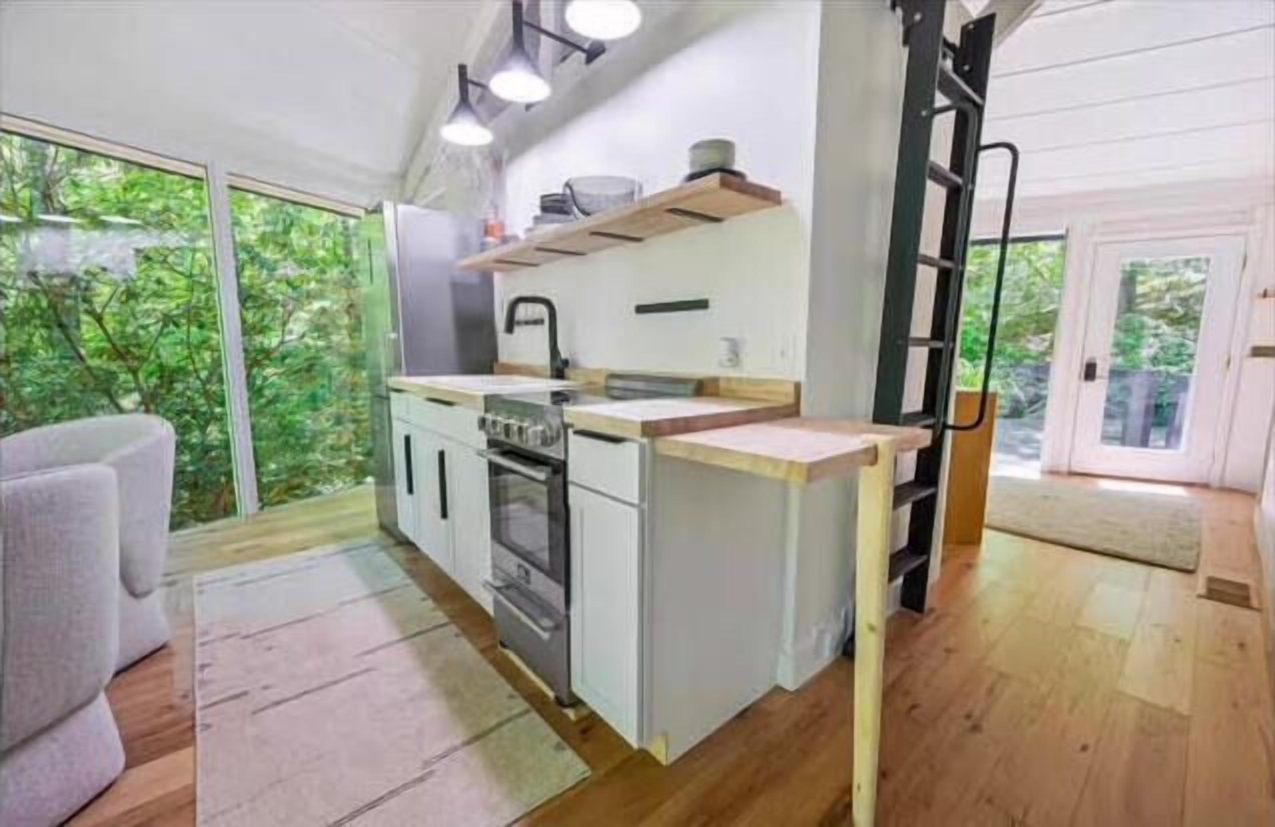 A compact kitchen with a central island, a built-in oven, and a window overlooking greenery.