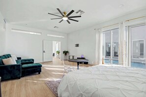 A modern bedroom with a large bed, a sofa, a small table, and a ceiling fan. - Executive Enterprise Retreat | Newly Renovated Desert Oasis (Las Vegas)