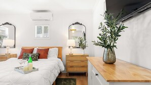 Une chambre à coucher avec un lit, des tables de chevet, une commode, un miroir et une plante en pot.