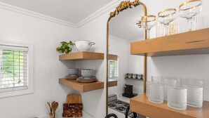 Une cuisine avec des étagères en bois, une cuisinière et un grand miroir.