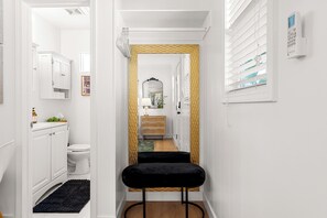 A narrow hallway with a black velvet bench, white cabinetry, a toilet, and a window with blinds. - Welcome to this cozy, stylish escape- private guesthouse in beautiful Redlands (Redlands)